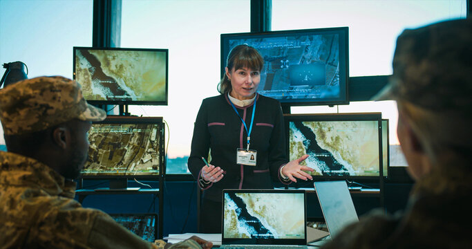 Caucasian teaching soldiers at special military lection and showing some videos on screen. Female talking to male and female mixed-races people from troops. Surveillance study concept.