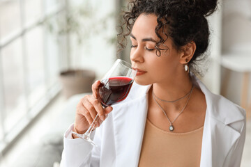 Young African-American businesswoman drinking red wine at home, closeup
