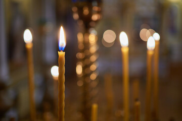 Burning church candles in a gilded candlestick in a temple in the dark