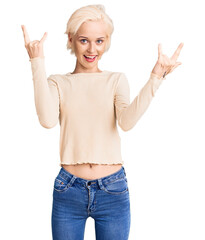 Young blonde woman wearing casual clothes shouting with crazy expression doing rock symbol with hands up. music star. heavy music concept.