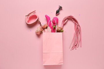 Paper bag with beautiful rose flowers and different sex toys on pink background