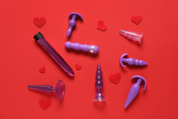 Composition with vibrator and anal plugs from sex shop on red background