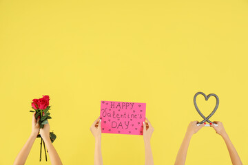 Female hands holding sign with text HAPPY VALENTINE'S DAY, bouquet of roses and heart on yellow background