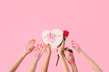 Female hands with paper hearts reaching for heart-shaped gift box and rose on pink background....