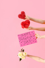 Female hands holding sign with text HAPPY VALENTINE'S DAY and different gifts on pink background