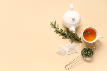 Teapot and cup of hot rosemary tea on beige background