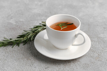 Cup of hot rosemary tea on grey background