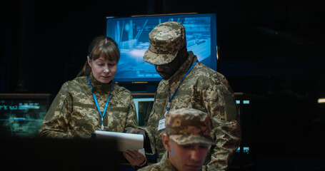 Mixed-races man and woman, officers in camouflage talking and discussing some official data in...