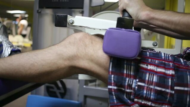 Man performs exercise for knees flexion in fitness center.