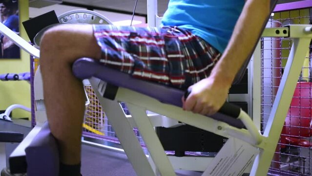Man performs exercise for knees extension in fitness center.