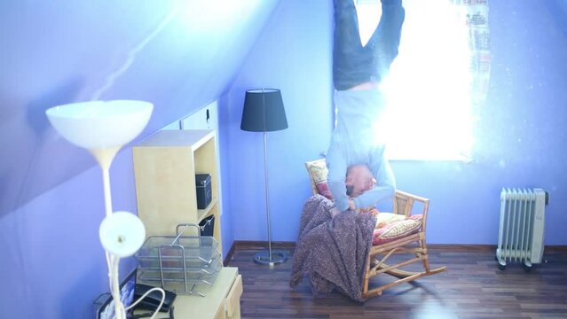 Man jumps on ceiling above armchair upside down at inverted house