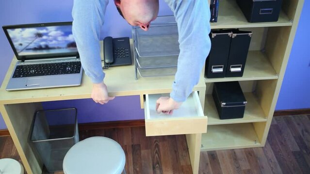 Man upside down opens desk drawer at inverted house