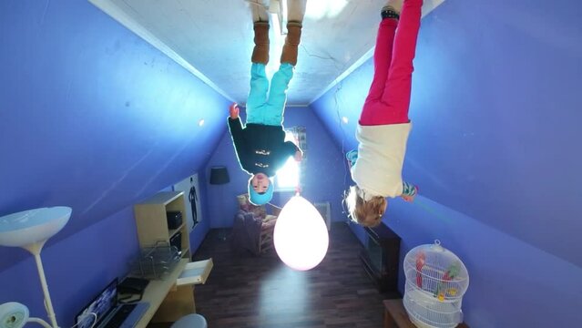 Little girl and boy with balloons on ceiling at inverted house