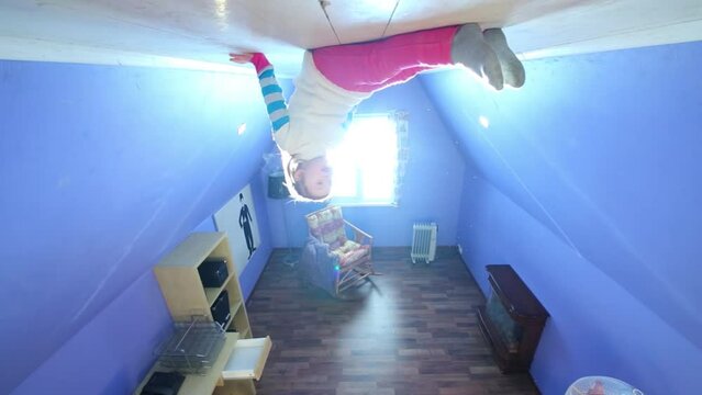 Little girl sits on ceiling upside down at inverted house