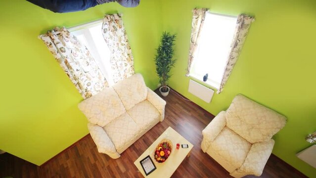 Man lies on ceiling above sofa without shoes in inverted house