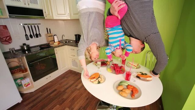 Father, mother, daughter upside down touch table in inverted house