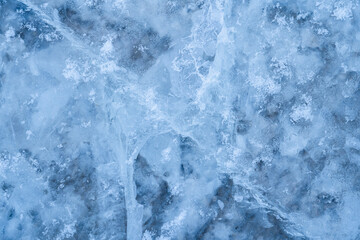 Fototapeta premium Icy winter background cracked grunge texture. Natural scratched ice on a skating rink as a texture or background for a winter composition, large long painting