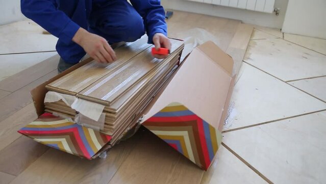 The man opens and breaks the box with the new flooring