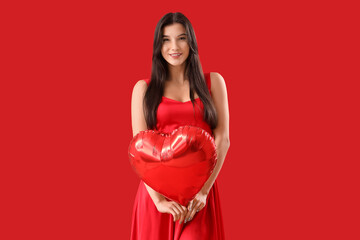 Beautiful young woman with heart-shaped air balloon on red background. Valentine's day celebration