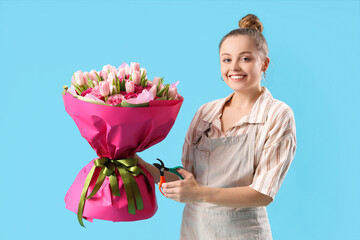 Beautiful young woman with bouquet of flowers and pruner on blue background