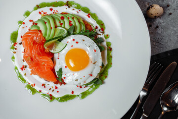 Poached eggs on top of smashed avocado on sourdough toast with smoked salmon. Healthy breakfast with plate on table. Top view. Copy space to right 