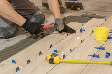 Repair and construction. Laying ceramic tiles using cement on the floor close-up. A man lays slabs...