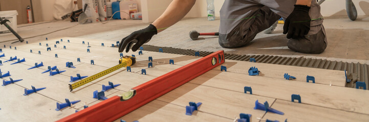 Repair and construction. Laying ceramic tiles using cement on the floor close-up. A man lays slabs on the floor and walls.