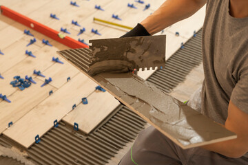 Repair and construction. Laying ceramic tiles using cement on the floor close-up. A man lays slabs on the floor and walls.