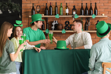 Group of young people with beer celebrating St. Patrick's Day at counter in pub