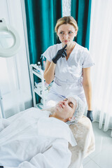 Obraz premium A smiling cosmetologist is doing a beauty procedure on her patient. Facial skin care. Cosmetology and dermatology.