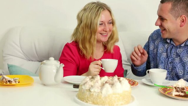 Young couple is talking and sitting on sofa at the birthday table