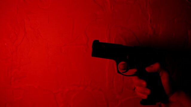 4K hand up holding gun. pistol hand close up. slow motion pistol gun shot imitation. pistol shooting gun hand. pistol hand hold. Red color cinematic background