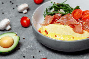Crepes with fried egg, Jamon slices, fresh tomatoes and cucumber fillings on a white plate on an old wooden table, view from above
