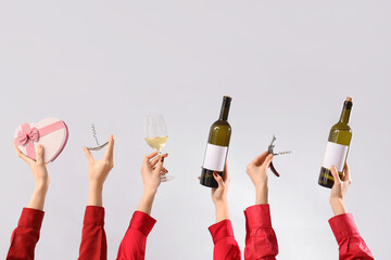 Women with wine, corkscrews and gift on light background. Valentine's Day celebration