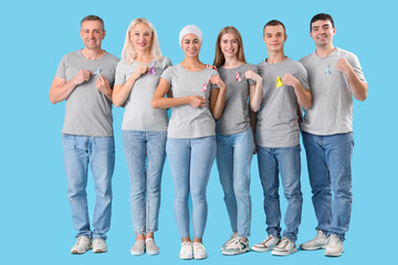 People with different awareness ribbons on blue background. World Cancer Day