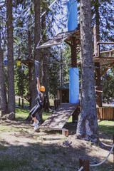 A fearless teenage girl at an adventure park in the forest.