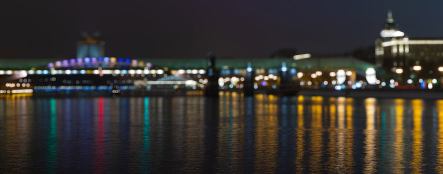 Night view with bokeh on the city lights. Abstract background of city at night. Reflection of lights in the river. Blurred bokeh city lights background