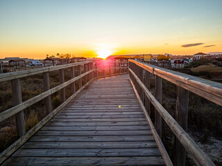 Wooden path leading to the beach at sunset by the sea