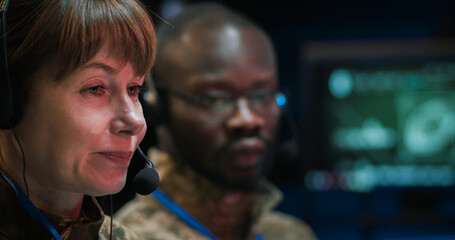 Close up of Caucasian middle-aged woman in headset talking via videochat in monitoring room in...