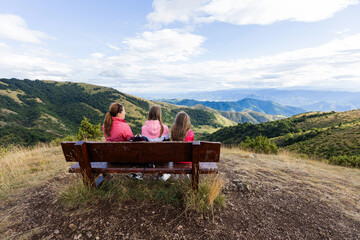 Family enjoying scenic mountain nature landscape view, sitting on the bench, feeling peaceful and...