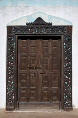 Alte braune Holztür mit Kassetten und einem Rahmen aus floralen Verzierungen - Betancuria,...