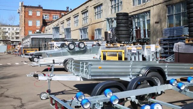 New utility trailers lined up and locked together outside.