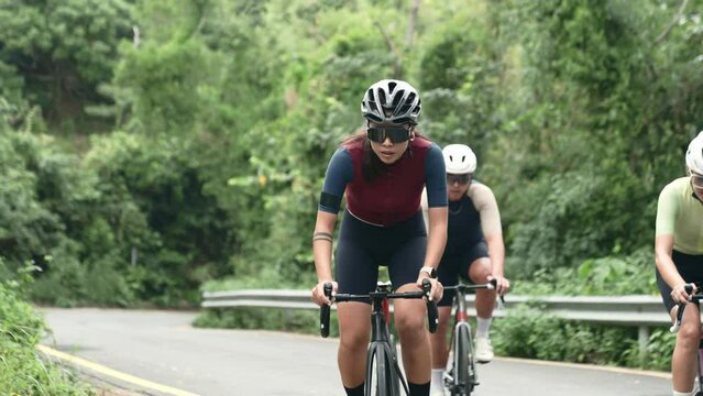 three young asian professional cyclists riding bike and training on rural road