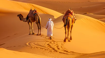 Fototapeten Camel rider with camels travelling over dunes in the desert © Eliya