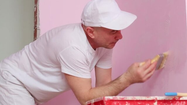 Colourer in white clothes and cap works in pink room