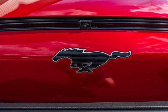 Lindesnes, Norway - August 06 2021: Pony logo in the front of a red Ford Mustang Mach-e electric car.