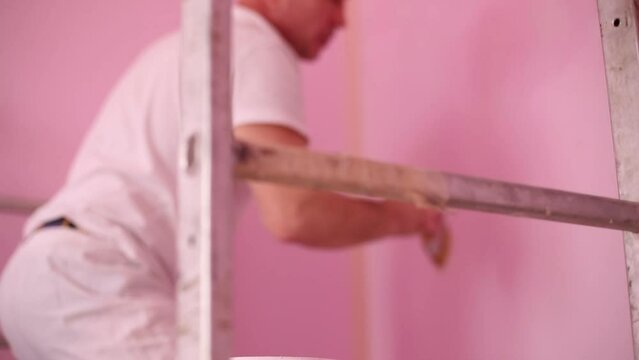 Colourer in white clothes and cap working in new room. 