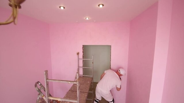 Top view of man with brush in hand working in pink room