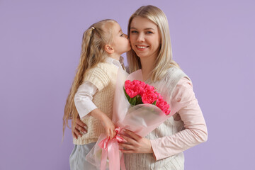 Little girl with tulips kissing her mother on lilac background. International Women's Day celebration
