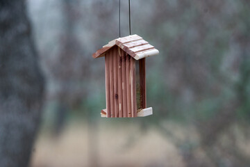 Small Cedar Hanging bird feeder with defused winter background